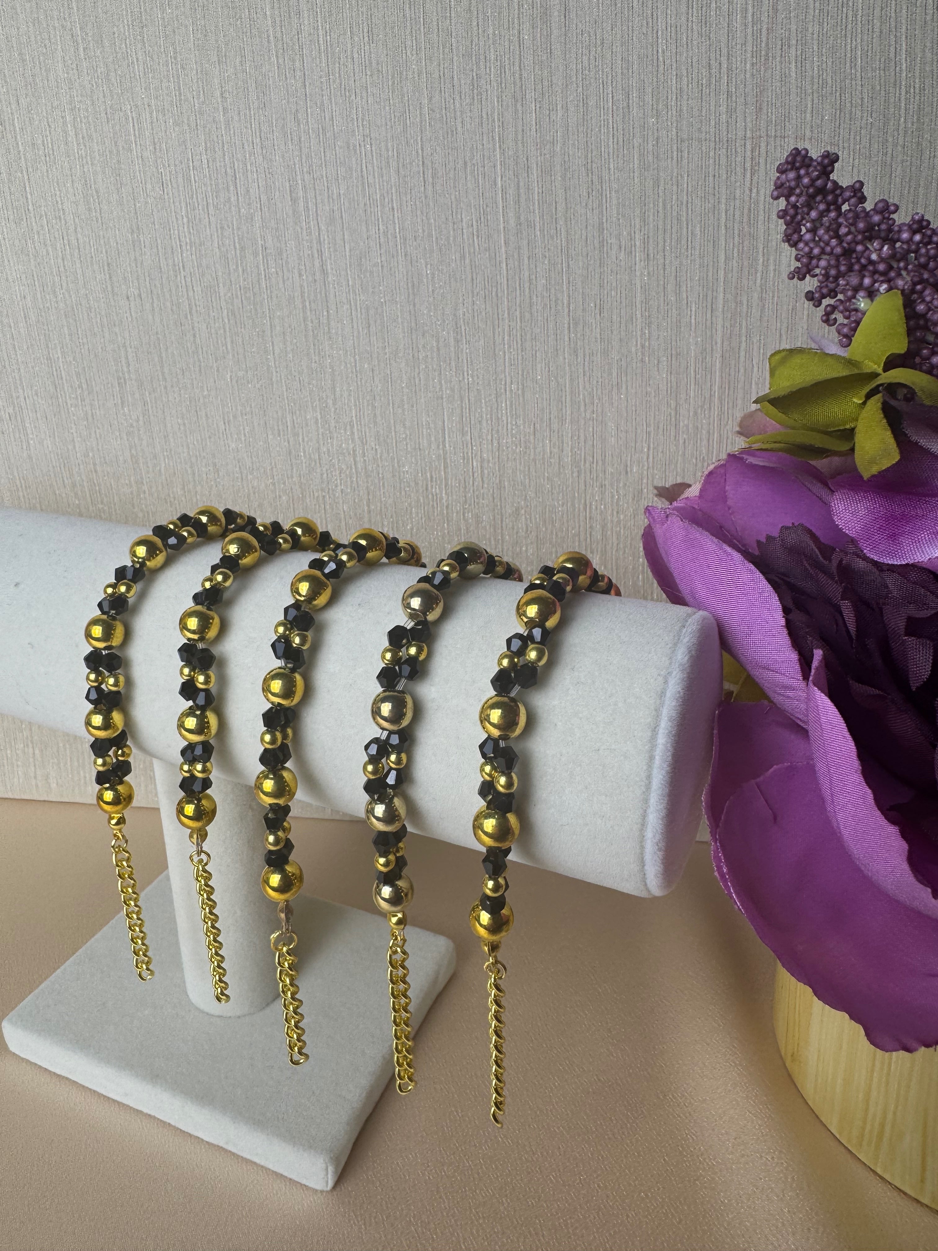 Three beaded bracelets on a white jewelry display stand.